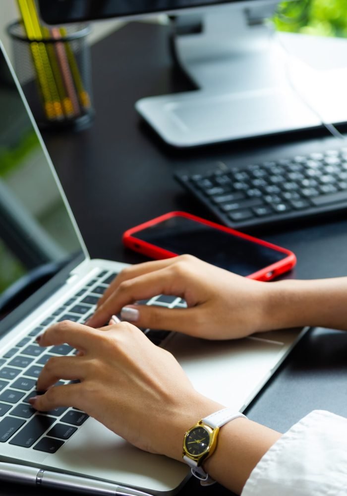 Female hand typing on keyboard of laptop Close up hand of female typing on keyboard of laptop on table, working with technology device in modern office